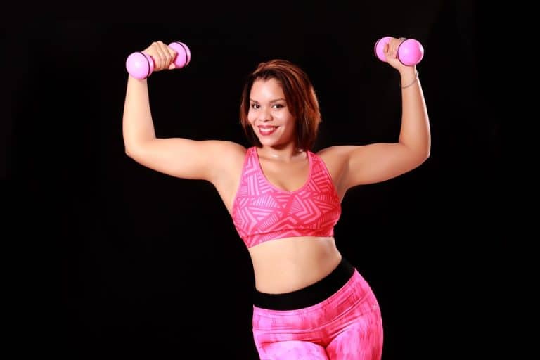 femme s'entraînant à la musculation à domicile avec des haltères roses