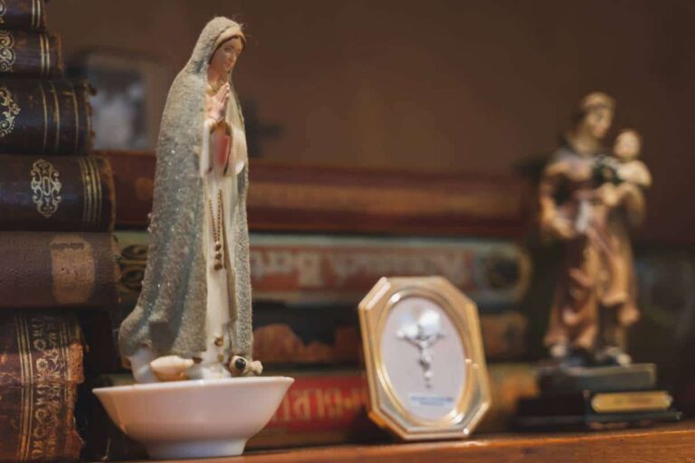 Statue de la Vierge Marie entourée de bougies sur une table de prière