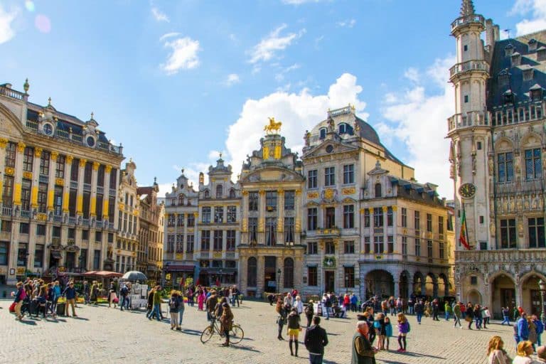 touristes admirant la Grand-Place de Bruxelles sous un ciel bleu