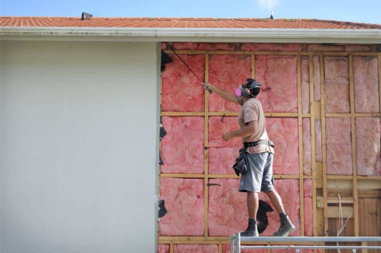 artisan effectuant des travaux d'isolation thermique sur une façade